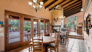 A dining area with wooden tables and chairs, a chandelier, and a fireplace. - Adobe Village Inn Painted Desert (Sedona)