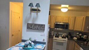 A kitchen with a central island, wooden cabinets, a microwave, stove, and a refrigerator.