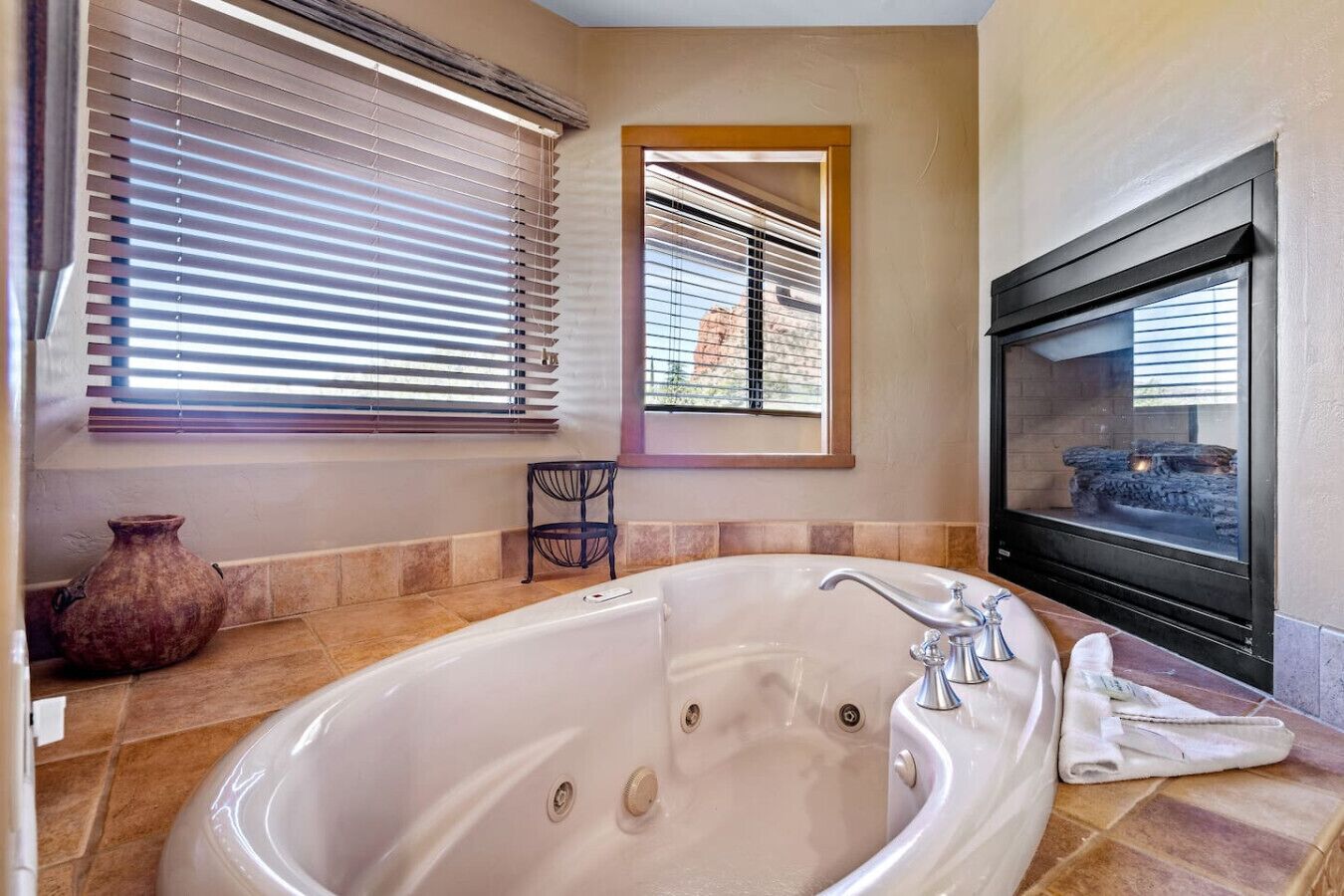 A bathroom with a large bathtub, a mirror, and a fireplace.