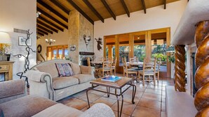 A spacious living area with a high ceiling, a fireplace, and a dining area with outdoor views.