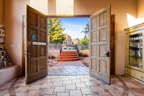 A hotel entrance with wooden doors, a stone pathway, and a view of a mountain landscape. - Adobe Village Inn Sedona Suite (Sedona)