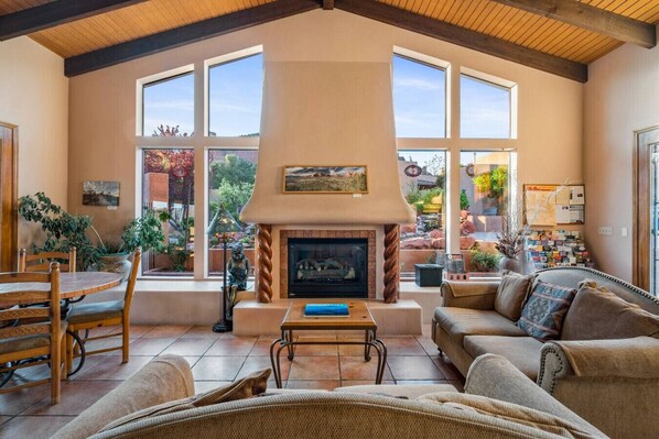 Una sala de estar con chimenea, ventanas amplias y un comedor con sillas y una mesa.