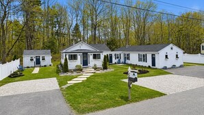A row of white single-story houses with a front lawn, a mailbox, and a white picket fence. - King Suite Getaway, Downtown Ogunquit. Walk to Beach, Shops & Dining! (Ogunquit)