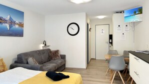 A modern hotel room with a bed, a sofa, a desk, and a television. - Apartment  by Interhome (Zermatt)