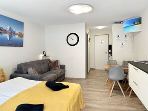 A modern hotel room with a bed, a sofa, a desk, and a television. - Apartment  by Interhome (Zermatt)