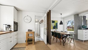 Ett modernt kök med vita skåp, en bänkskiva i trä och en inbyggd ugn.