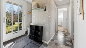 En modern inredning med en vägg i betong som accent, en svart hyllsektion och ett golv med hexagonformade plattor.