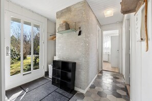 Et moderne interiør med en væg i beton, en sort reol og gulv med hexagonfliser.
