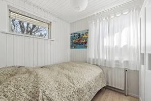 A bedroom with a bed, a window, a radiator, and a painting on the wall. - Cozy holiday home near the beach and Gilleleje (Gilleleje)