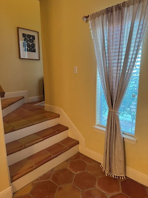 A staircase with brown steps leading to a window with a curtain.