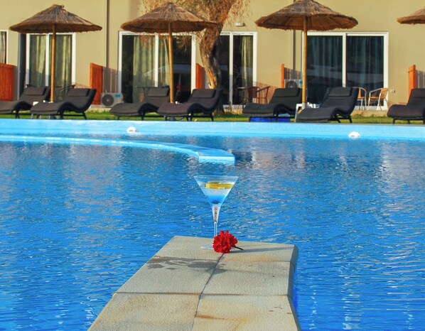 Una piscina con sillones de descanso y sombrillas.