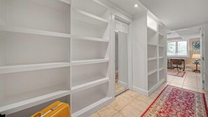 Una habitació àmplia amb prestatgeries integrades, una maleta groga i un tapet vermell amb dibuixos.