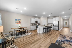 Una cocina moderna con armarios blancos, electrodomésticos de acero inoxidable y una isla central.