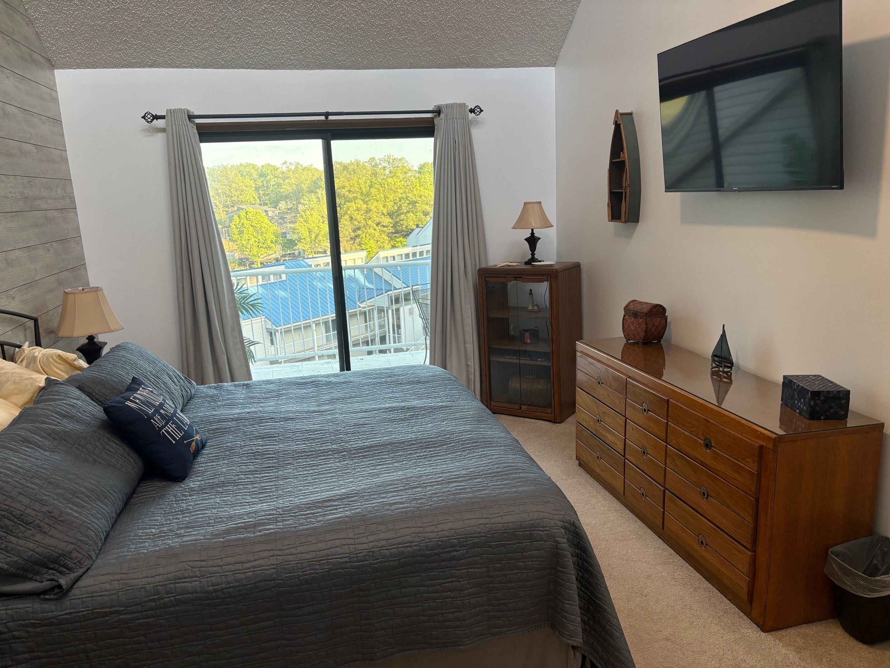 Ein Schlafzimmer mit Bett, Kommode, Lampe und Fernseher.