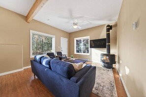 A living room with a sofa, chairs, a fireplace, and large windows. - Timberline | 2 Full Suites | Backyard | Pets Ok (Invermere)