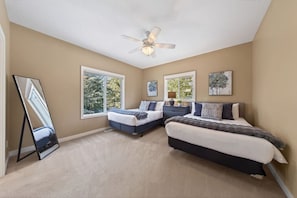 A bedroom with two beds, a ceiling fan, large windows, and artwork on the walls. - Timberline | 2 Full Suites | Backyard | Pets Ok (Invermere)