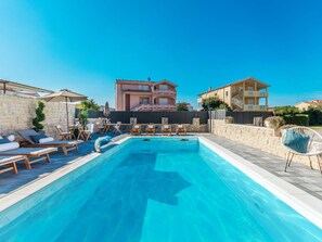 A swimming pool with lounge chairs and a stone wall. - Apartment  by Interhome (Biograd na Moru)