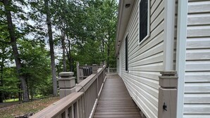 A wooden deck leading to a house with a white exterior, surrounded by trees. - La Buena Vida Retreat  Hot Tub • Game Room • Fire Pit (Huddleston)