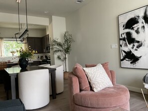 Ein modernes Wohnzimmer mit Essbereich, einem großen abstrakten Gemälde und einem Topf mit Pflanze.