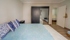 A bedroom with a bed, bedside tables, a wardrobe, and a mirror. - Apto a 750m da Praia da Enseada com Ar e Wi-fi (Guarujá)