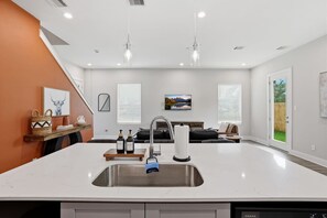 A modern kitchen with a central island, a built-in dishwasher, and a large window. - Texas Stylish Living North of Downtown Houston! (Houston)
