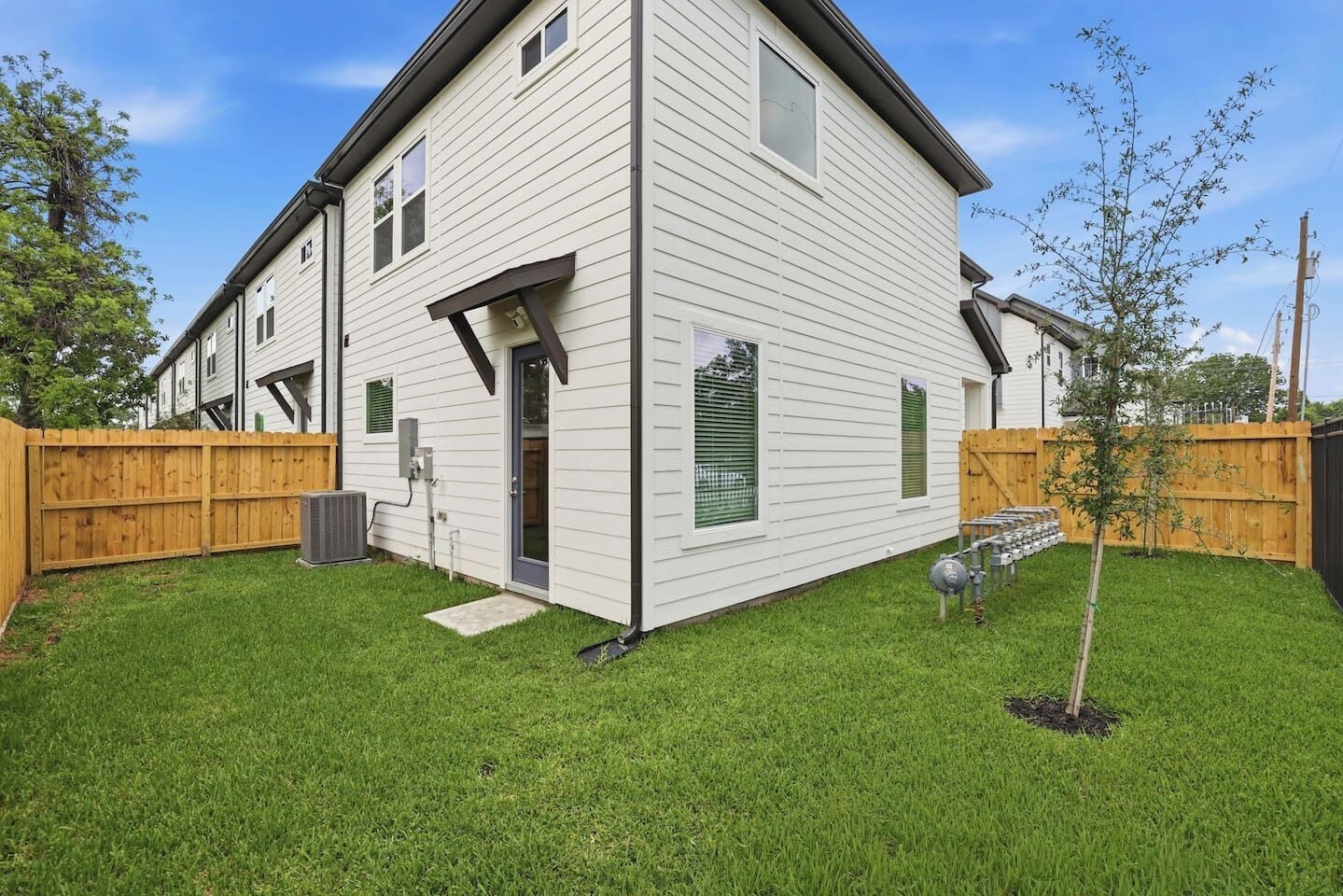 A two-story house with a front door, a small porch, and a fenced backyard.