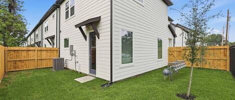 A two-story house with a front door, a small porch, and a fenced backyard.