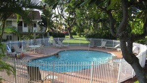 A swimming pool surrounded by a white fence, with lounge chairs and a table nearby. - 2-bedroom ocean golf course condo in beautiful Kailua-Kona w/ cool ocean breezes (Kailua-Kona)