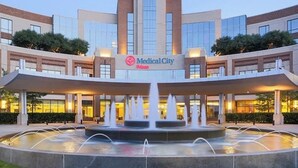 A modern building with a central fountain, a sign reading 'Medical City,' and a covered entrance area.