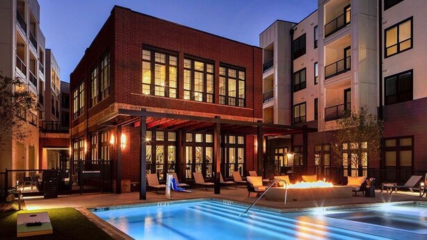 A building with a pool, outdoor seating, and a covered area.