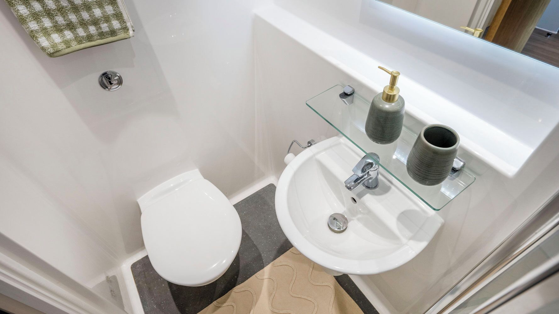 A bathroom with a toilet, a sink, and a glass shelf with toiletries.