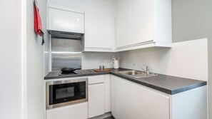 A compact kitchen with a built-in oven, microwave, stainless steel sink, and white cabinetry. - For Students Only Holden Court in Brighton (Brighton)