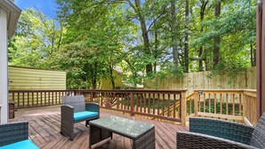 A wooden deck with wicker furniture and a view of trees. - 3-bedroom Comfy Townhome, less than 10 min from the Battery, Bring the Family (Marietta)