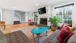 A living room with a fireplace, a television, and a staircase. - 3-bedroom Comfy Townhome, less than 10 min from the Battery, Bring the Family (Marietta)