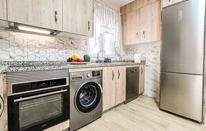 A modern kitchen with a stainless steel refrigerator, a built-in oven, a washing machine, and a dishwasher. - Lovely home in Totalan with WiFi (Totalan)
