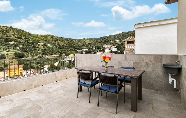 A terrace with a table and chairs, a vase of flowers, and a view of a hillside with buildings. - Lovely home in Totalan with WiFi (Totalan)