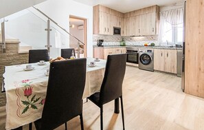 A modern kitchen with wooden cabinets, a built-in microwave, and a washing machine. - Lovely home in Totalan with WiFi (Totalan)