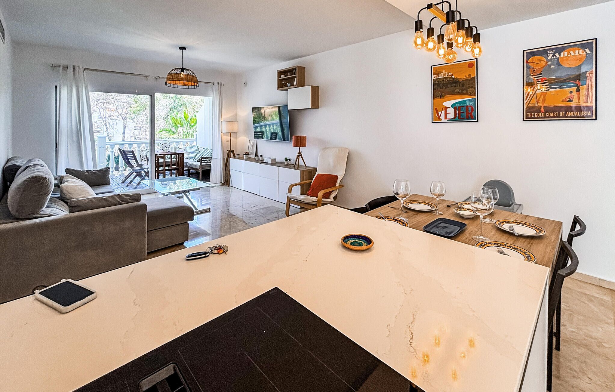 Un salon moderne comprenant un coin repas, un canapé, un téléviseur et une table mise pour le dîner.