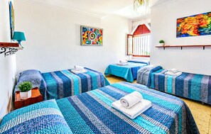 A hotel room with two single beds, a small table with a plant, a colorful abstract painting, and a window with curtains. - Stunning home in Prado del Rey (prado del Rey)