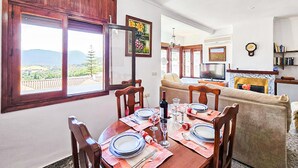 Un coin repas avec une table dressée pour quatre personnes, un canapé, un téléviseur et une cheminée.