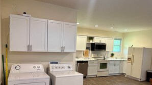 Una cocina con armarios blancos, microondas, horno, lavavajillas y refrigerador.