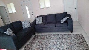 A living room with two dark sofas, patterned throw pillows, a patterned rug, and a white door with a window. - Hilltop overlooking the stunning beach at Love Hill, Central Andros Island. (Andros Island)