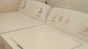 A white, wall-mounted washer and dryer unit with control knobs and a power cord plugged in. - Hilltop overlooking the stunning beach at Love Hill, Central Andros Island. (Andros Island)