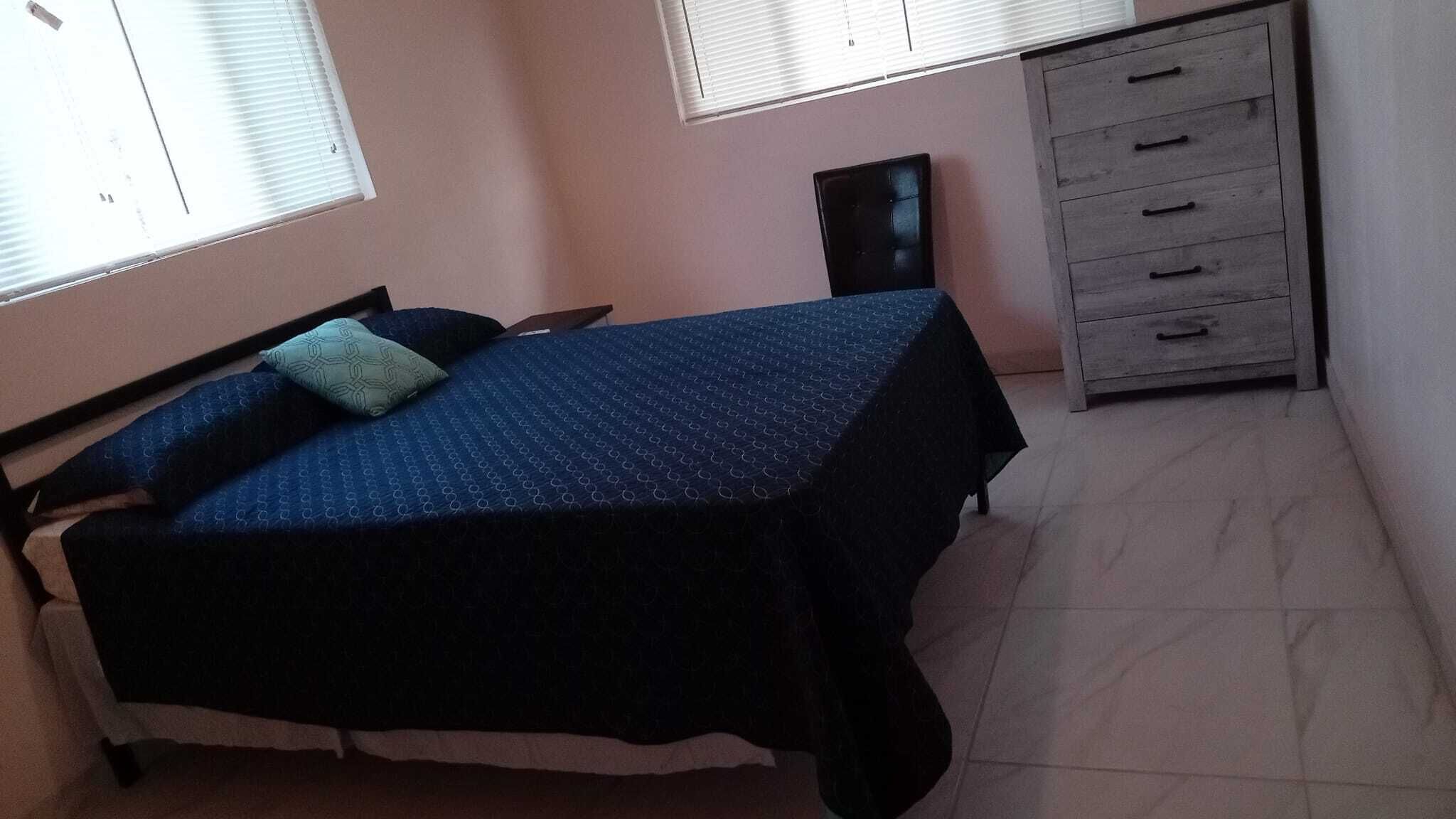 Une chambre à coucher avec un lit, une commode et une fenêtre.