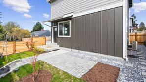 Une maison moderne avec une façade grise, un porche et un petit jardin.