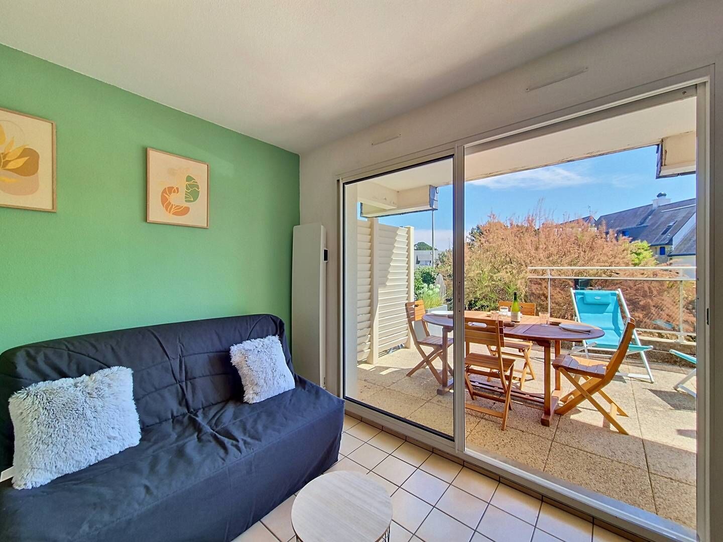 A room with a dark-colored sofa, a glass door leading to an outdoor area with a pool and patio furniture.
