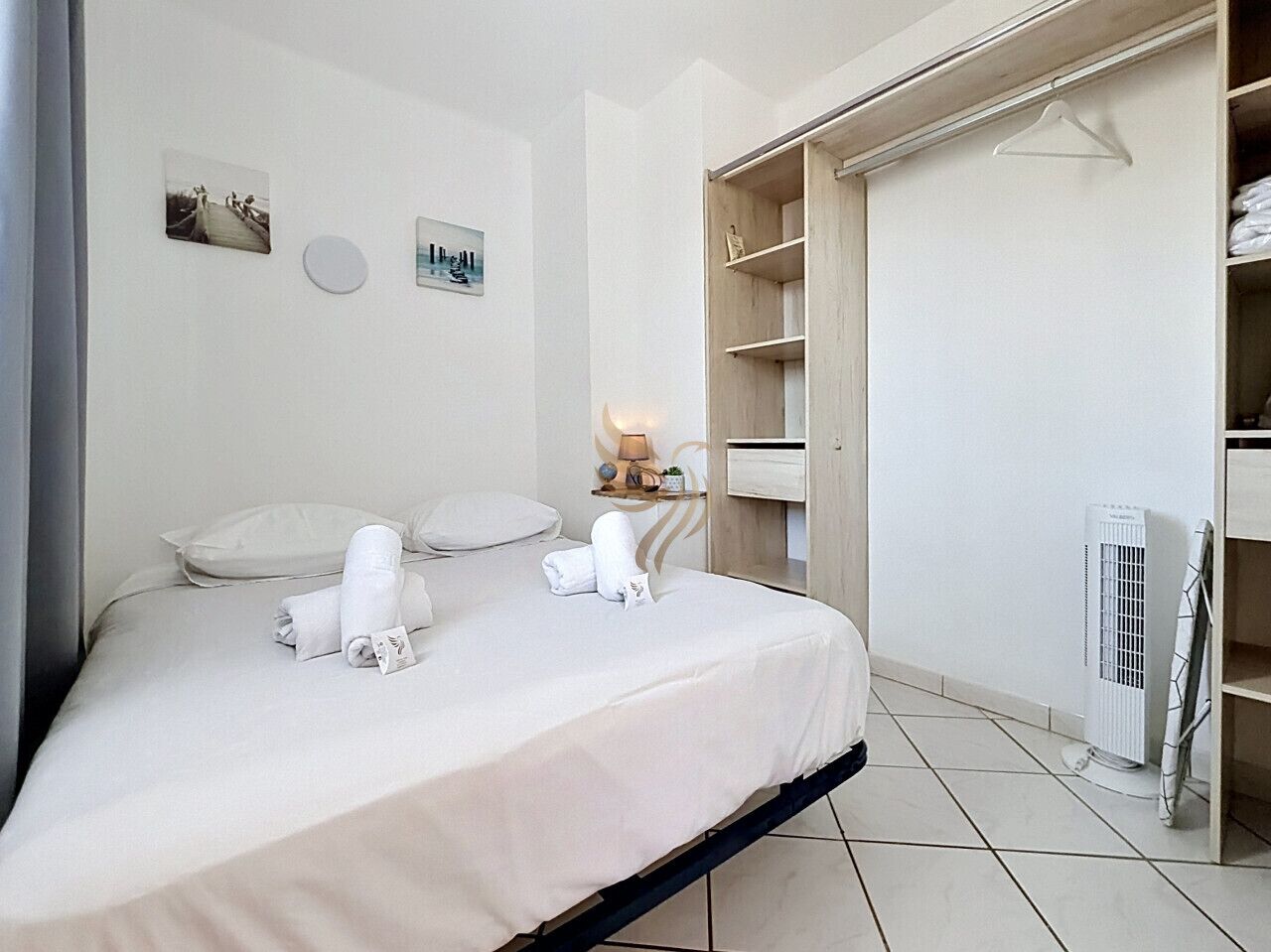 A hotel room with a bed, a bedside table with a lamp, a wardrobe, and a radiator.