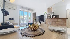 Comedor con mesa dispuesta para cuatro, un centro de mesa decorativo y un televisor al fondo.
