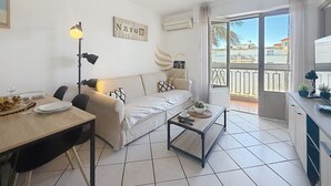Una sala de estar moderna con un sofá, una mesa de comedor y un balcón con vistas.