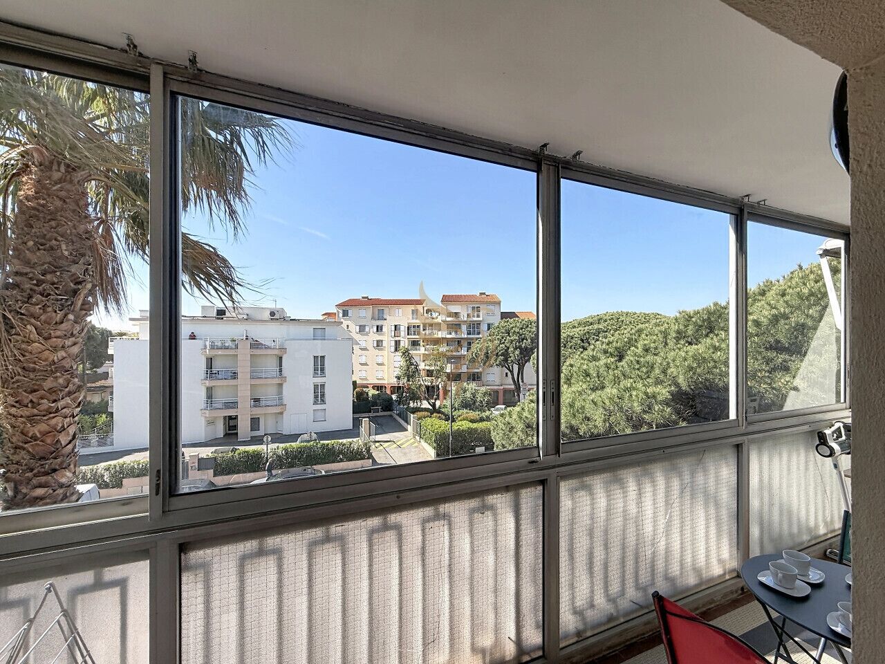 A balcony with a view of residential buildings and a palm tree.